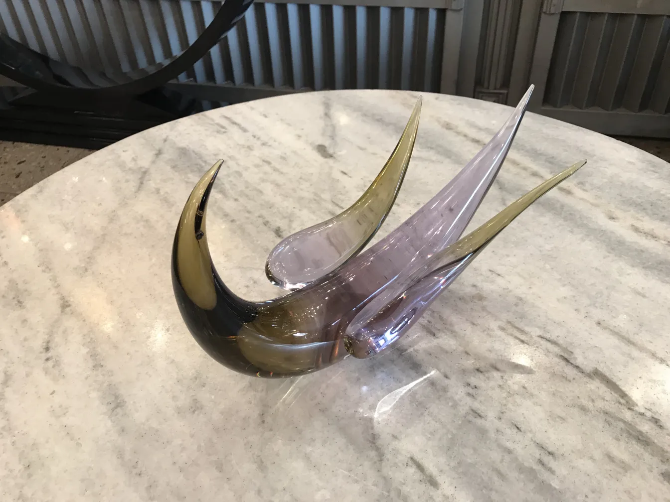 Murano sculpture with elegant and sinuous shapes on a marble table.