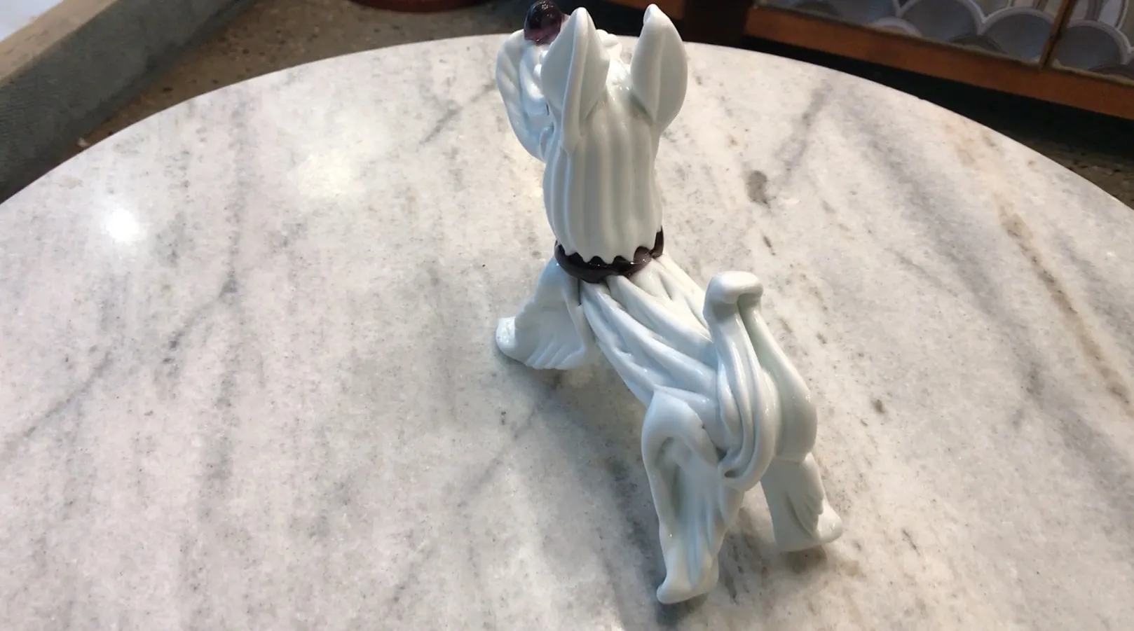 Scultura murano di un cane bianco su una superficie lucida.