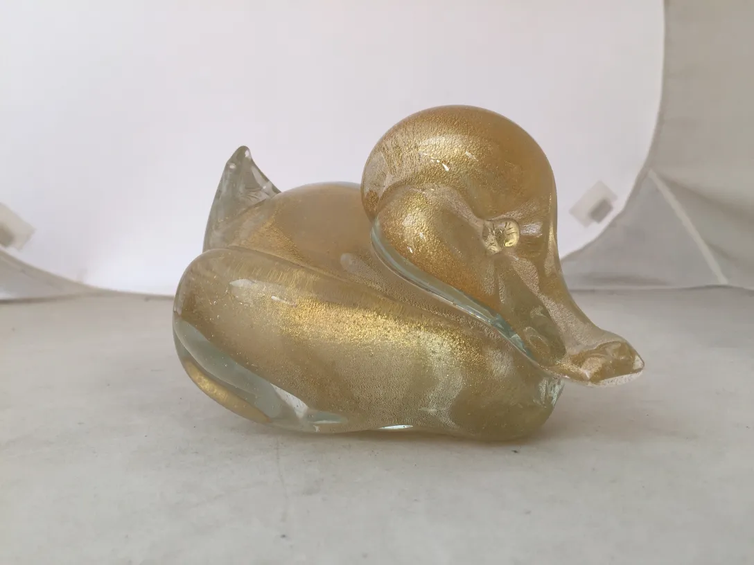 Elegant Murano sculpture shaped like a duck in golden tones against a white background.