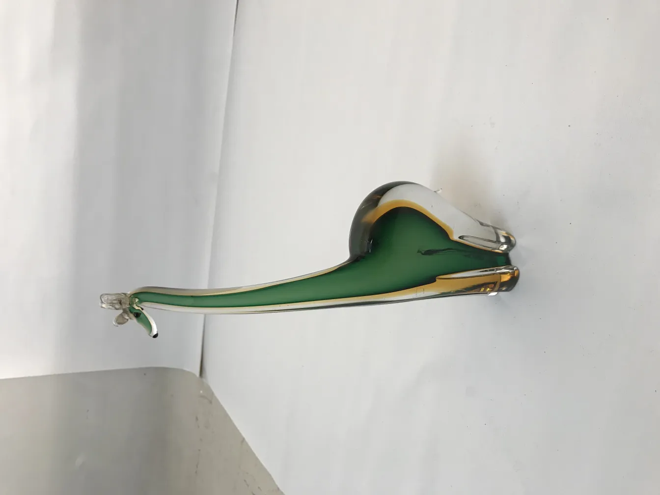 穆拉诺雕塑呈绿色和金色调，展现优雅的轮廓。中性背景