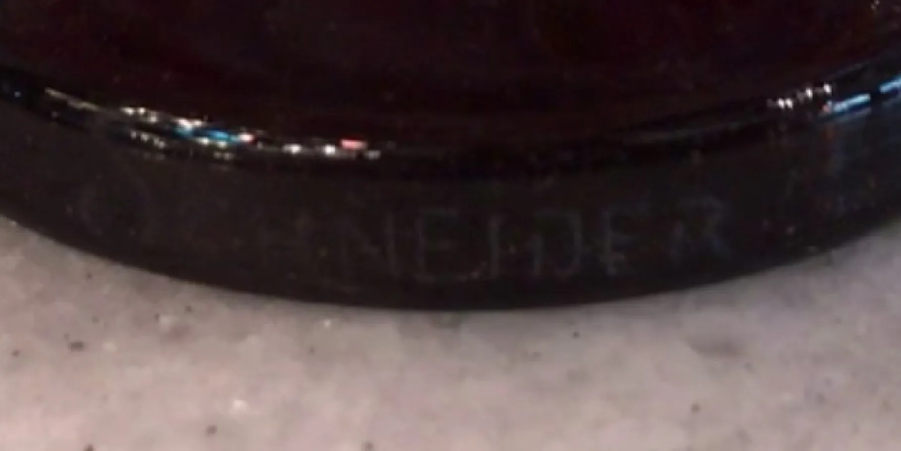 Vidro assinado Schneider com design antigo em fundo neutro.