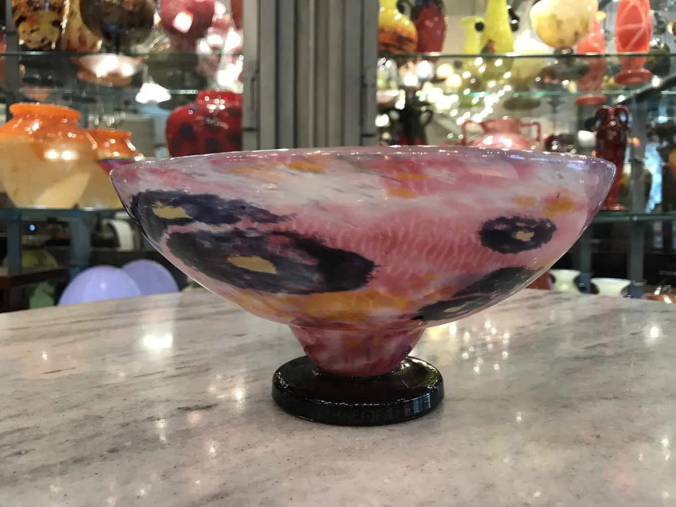 Antique bowl of signed glass by Schneider with vibrant colors in an antique setting.