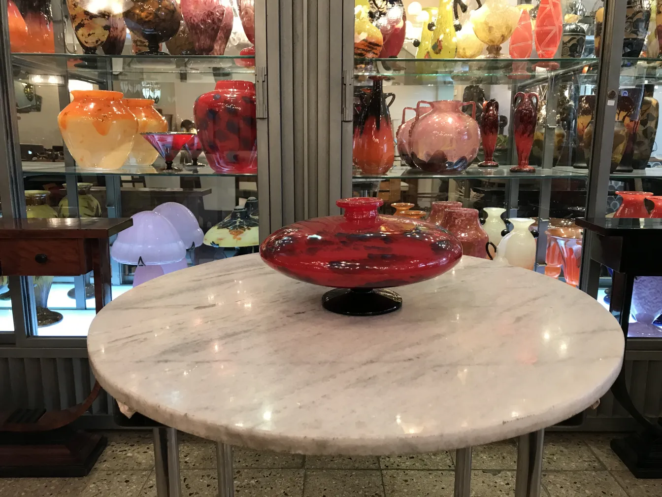 Round signed glass by Schneider with black base, antique, surrounded by various vintage pieces.