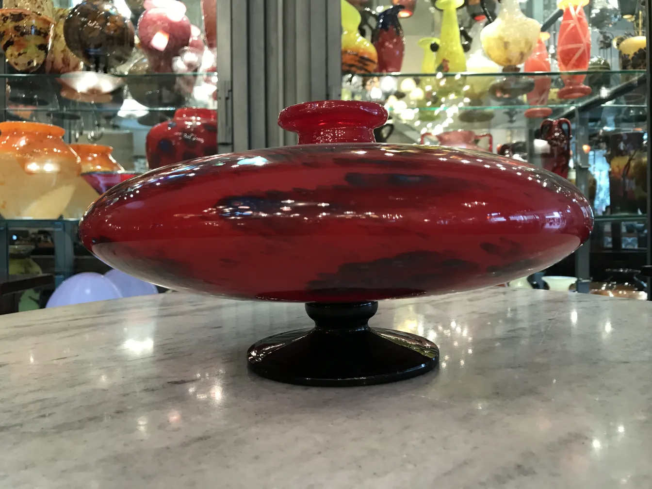 Verre signé rouge avec base noire et décorations.