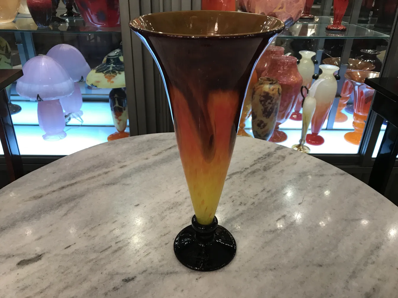 Vaso in vetro firmato Schneider con tonalità calde e colorate, circondato da antiquariato.