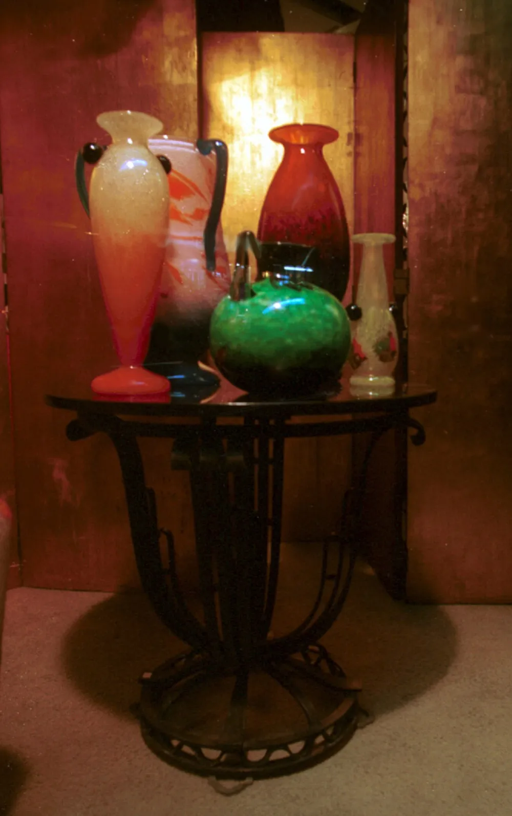 signed glass in green, red, and orange tones on a decorative table