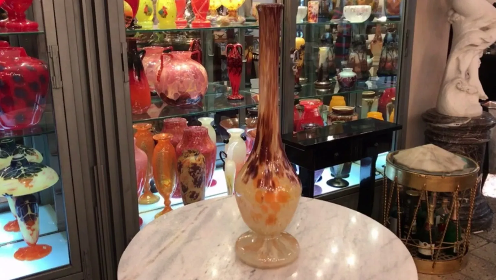 Vetro antico firmato da Schneider con dettagli artistici e oggetti colorati sullo sfondo.