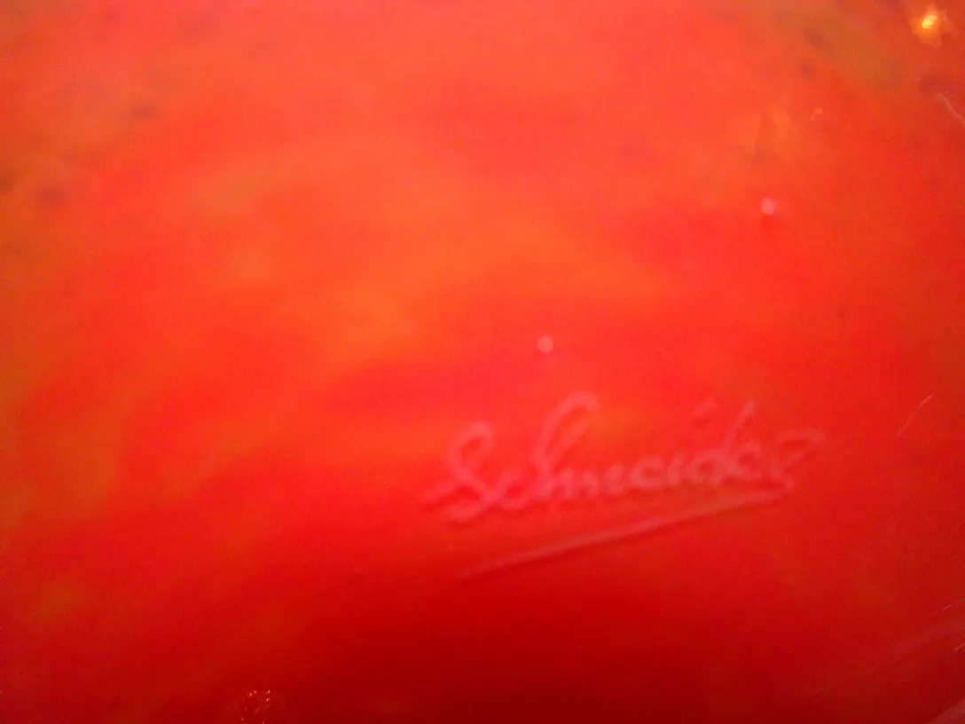 verre signé sur fond rouge avec signature visible