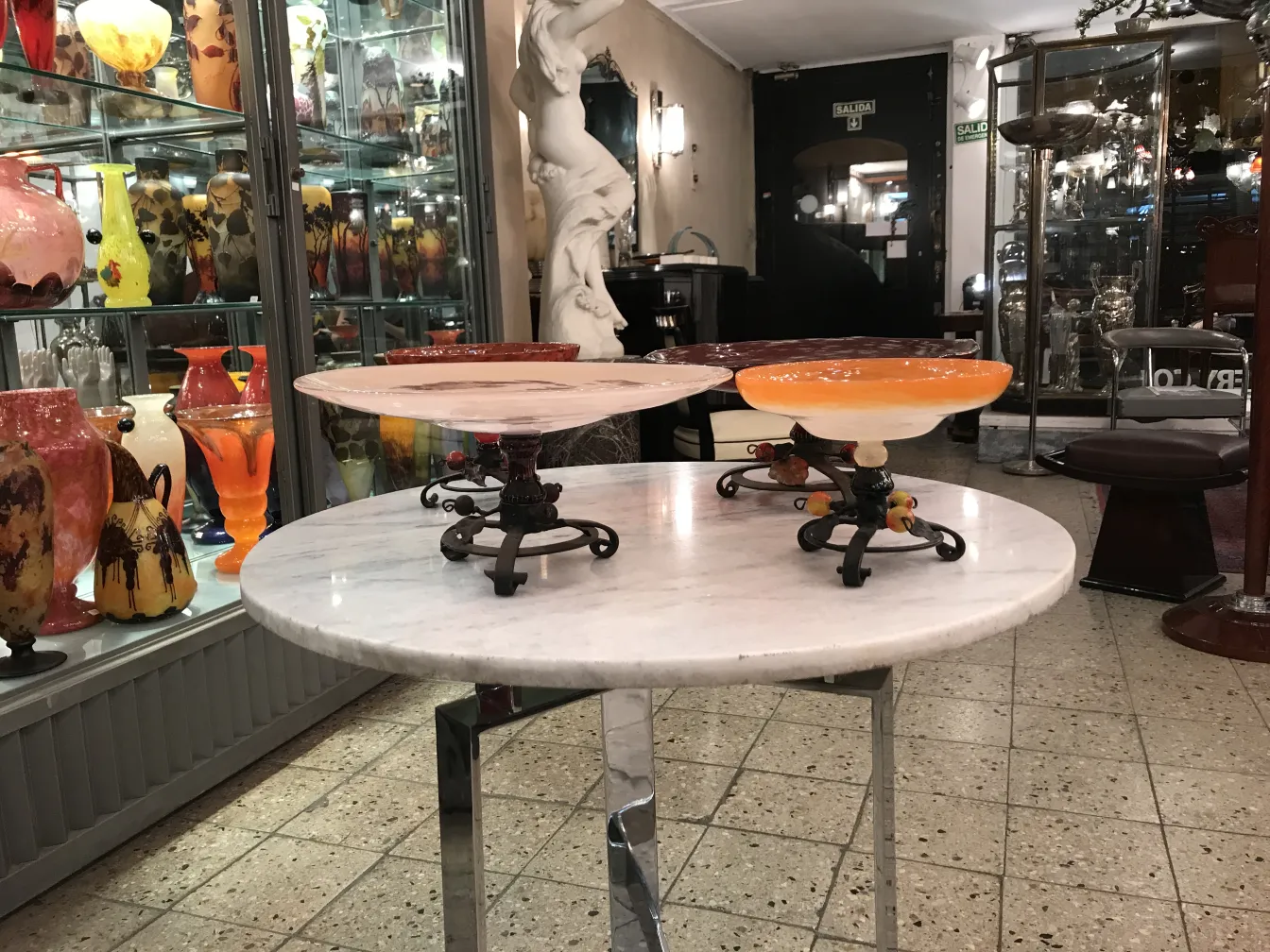 Vidrio antiguo firmado de Schneider con pedestal decorativo, exhibido entre otros frascos coloridos.