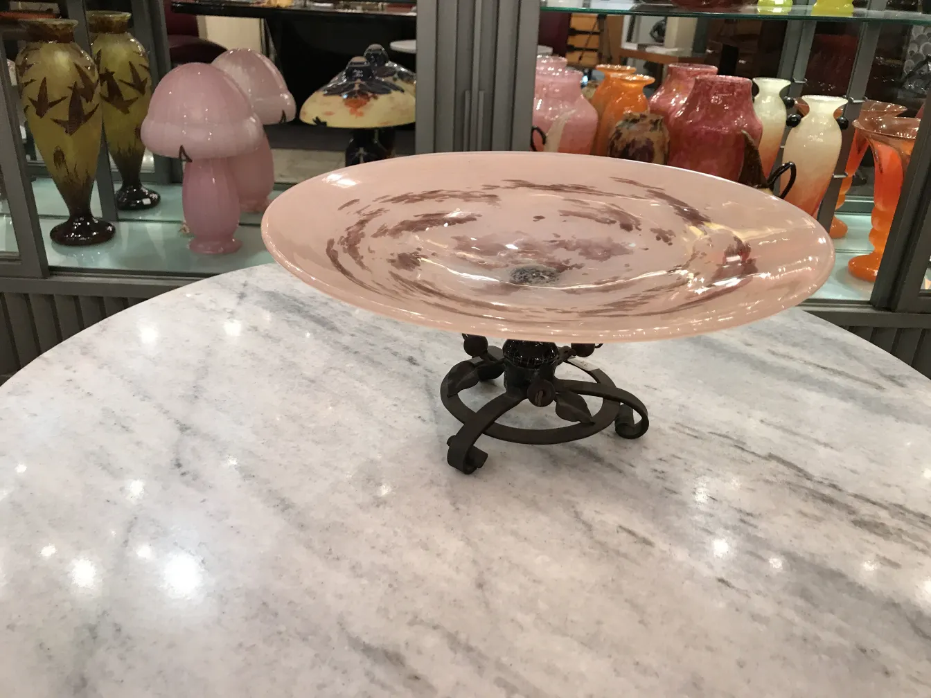 Prato decorativo de vidro assinado por Schneider em um ambiente de antiguidades.