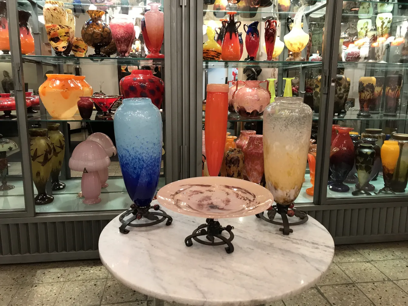 Vidrio firmado Schneider en una vitrina antigua con otros objetos decorativos coloridos.