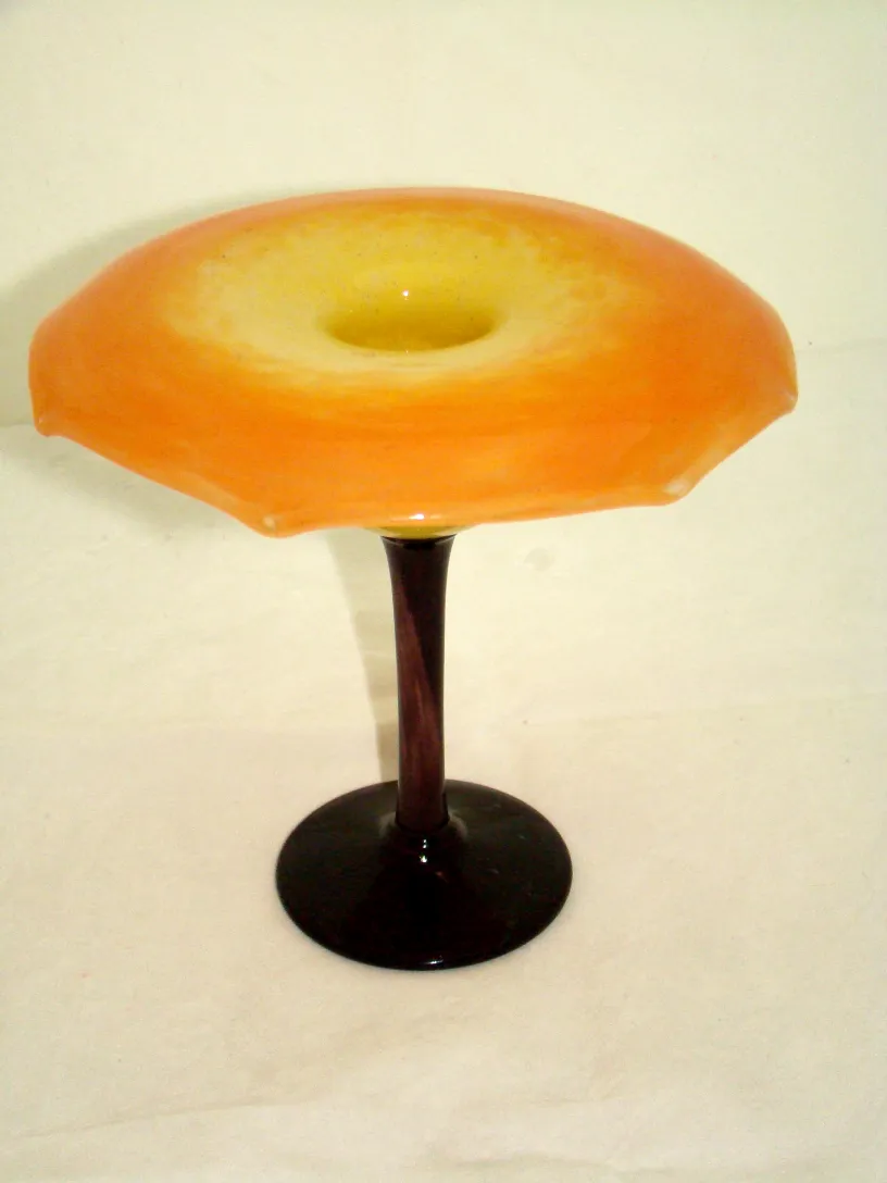 vidrio firmado de color naranja y amarillo elevado sobre una base