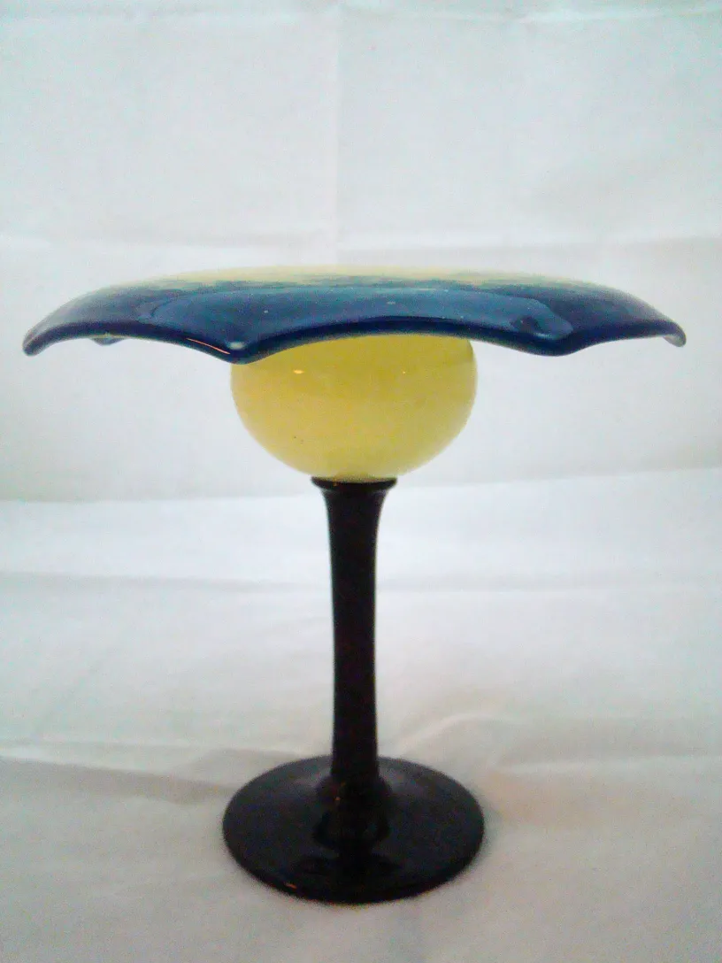 Yellow and blue signed glass with black stand.