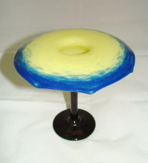 vidrio firmado con un diseño azul y amarillo, base negra