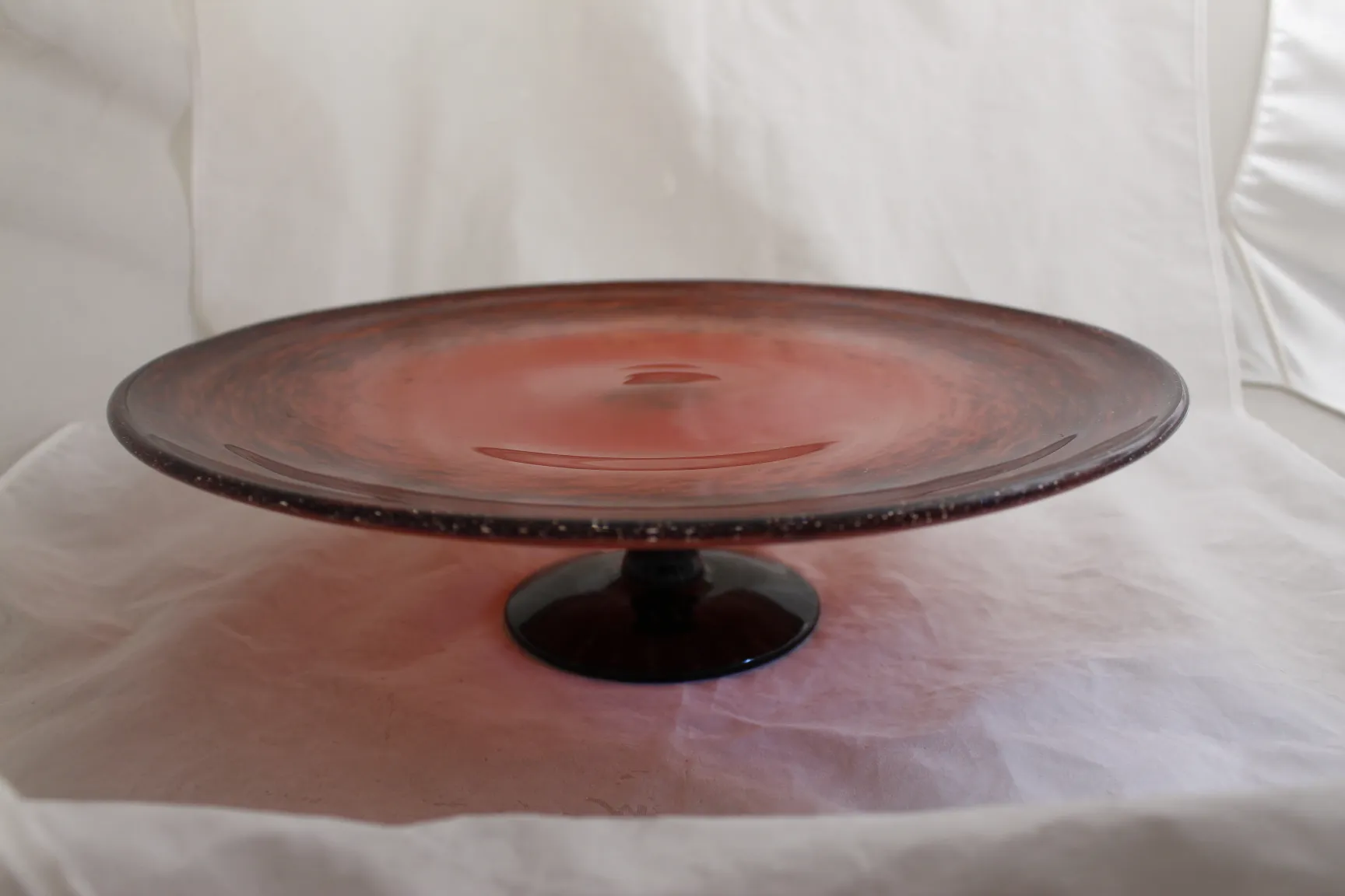 Antiker Glass Teller mit Fuß, rosa Farbe und elegantem Design.