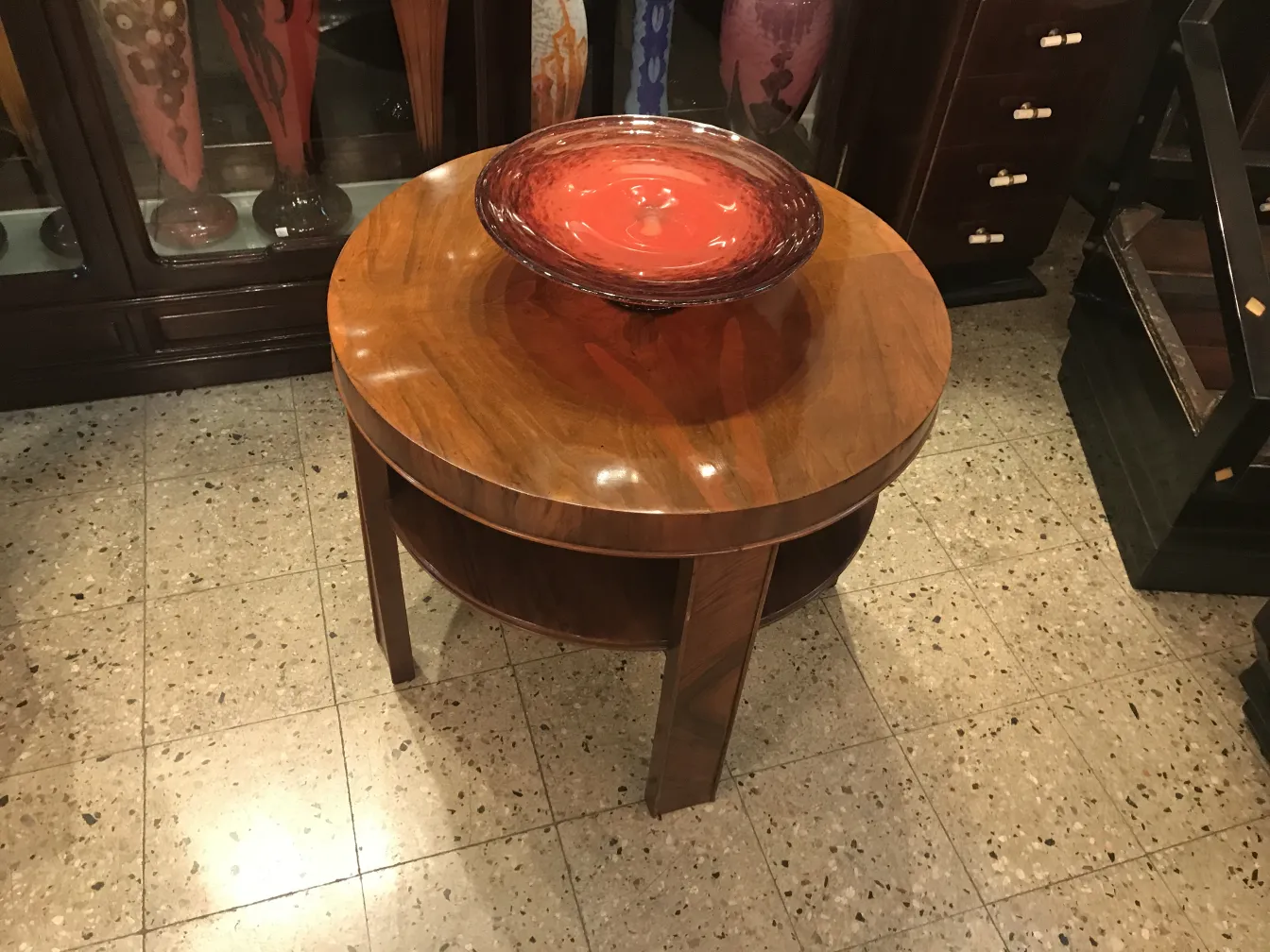 Recipiente redondo de vidrio con firma en centro sobre mesa de madera