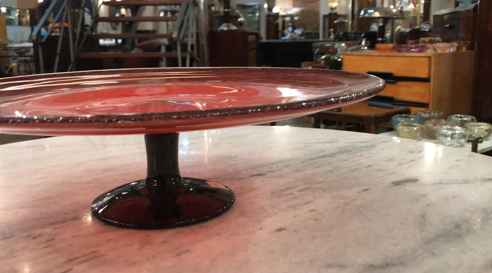 Vue de côté d'un verre signé Schneider français sur marbre, avec un fond d'antiquités.