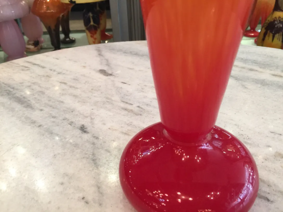 Vidrio antiguo firmado por Schneider, de color naranja y rojo, en ambiente elegante.