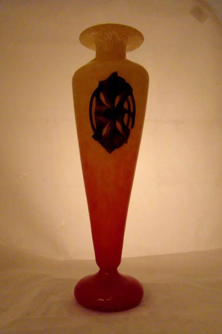 Vase en verre signé avec un design sombre, fond doux.