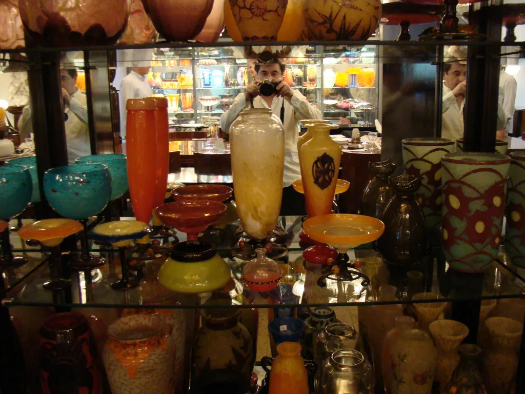 antique signed glass by Schneider on display shelf with other decor items