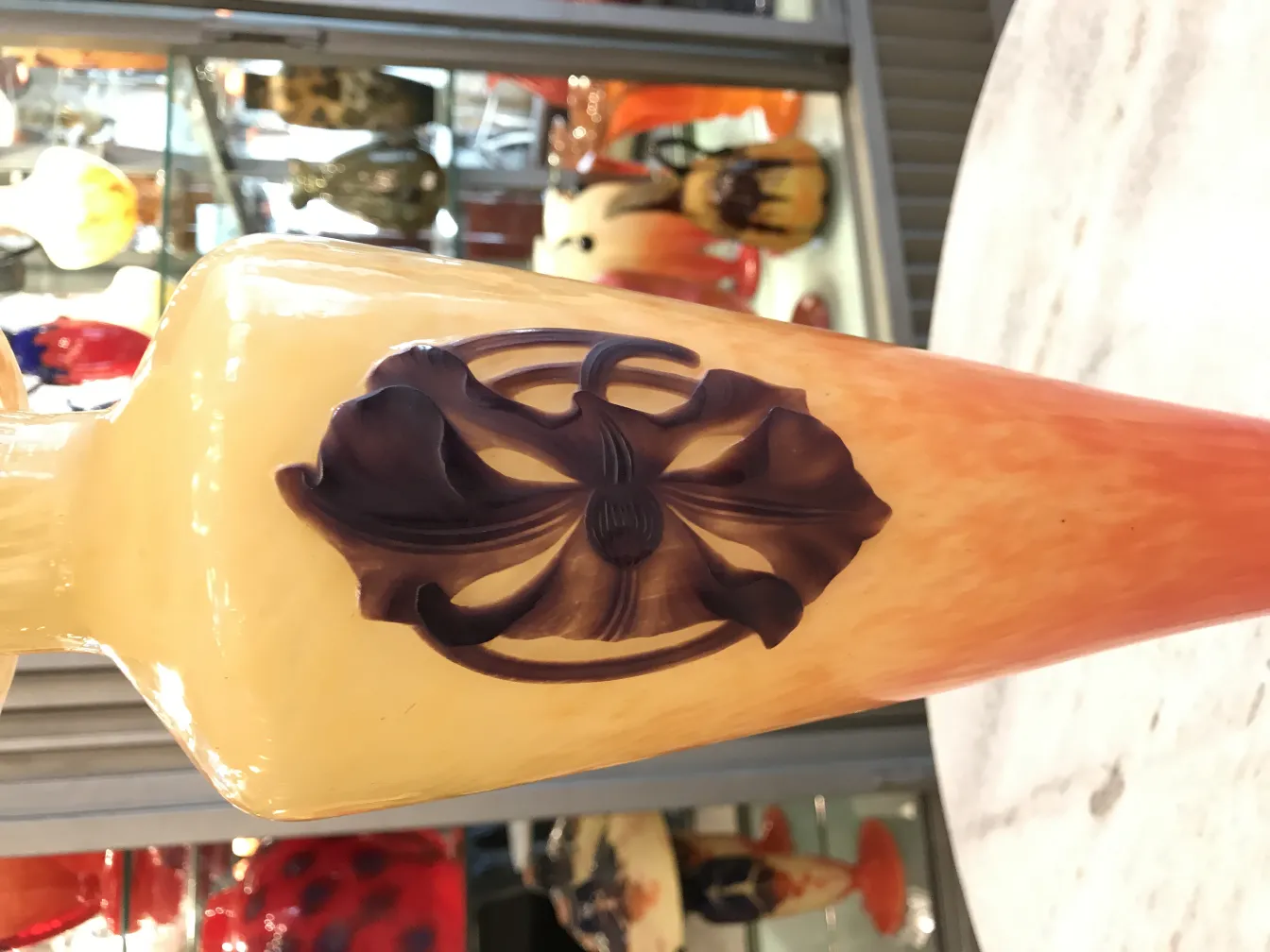 Vaso in vetro antico con design floreale in rilievo e firma visibile.