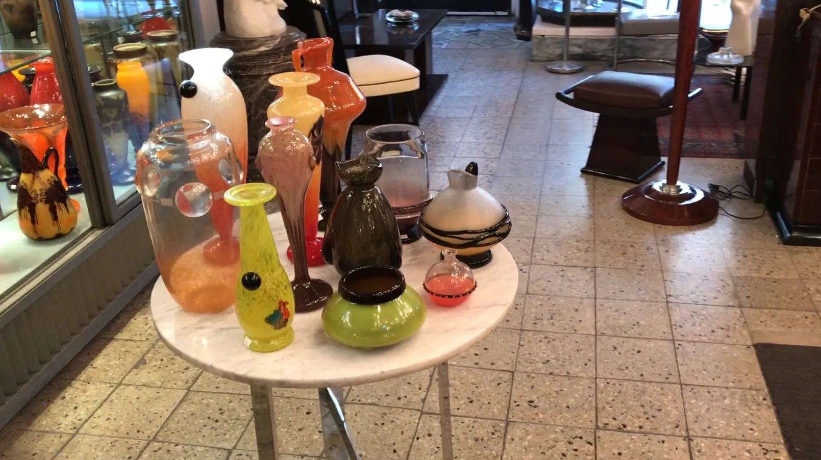 Vidro antigo assinado de Schneider em um ambiente com outros objetos decorativos coloridos.