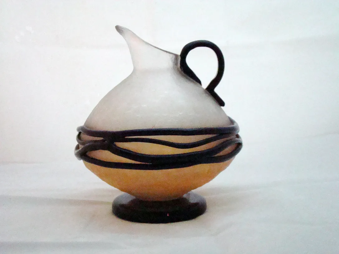 Ancien verre signé de forme ronde avec anse, décoré de fil. Fond neutre.