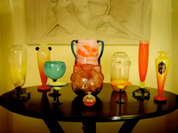 Collection of antique signed glass Schneider on the table, featuring various colors and shapes.