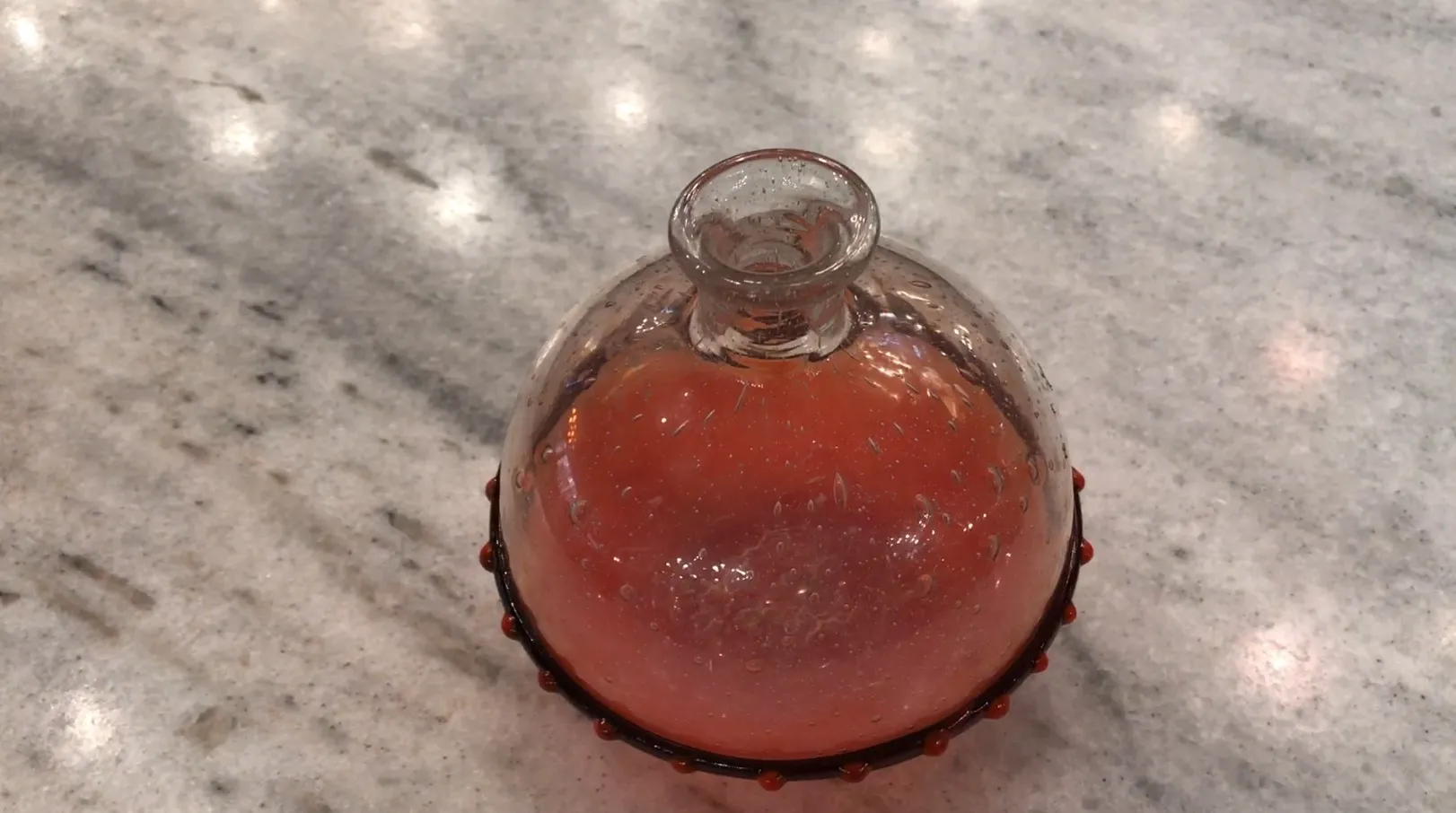 Antique signed glass by Schneider with distinctive shape and vibrant color, displayed on a marble surface.