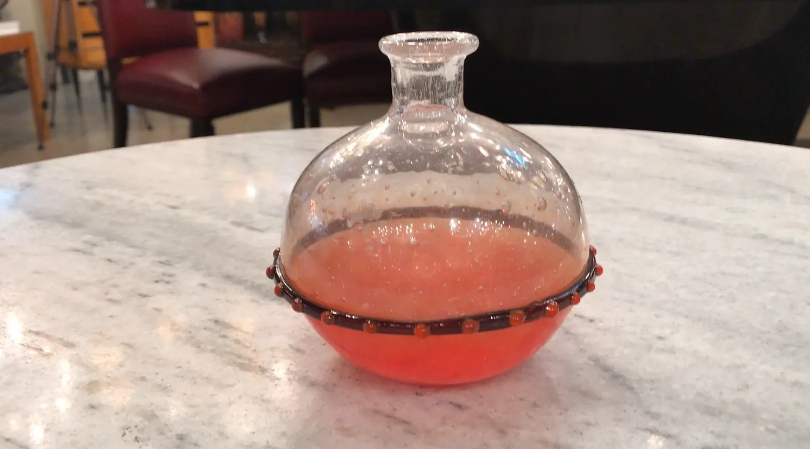 rundes signiertes Glas mit einem bunten dekorativen Band, auf einem Tisch