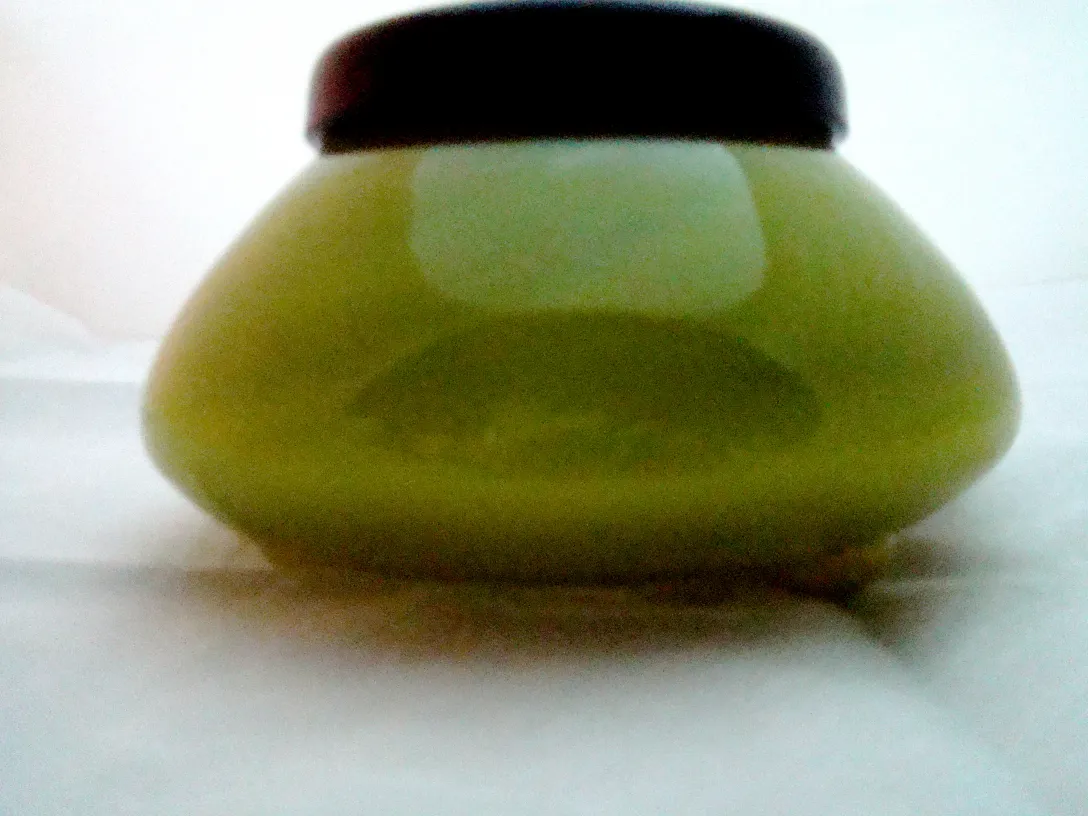 Vetro firmato antico in tonalità verde con coperchio scuro, presenta un design elegante.