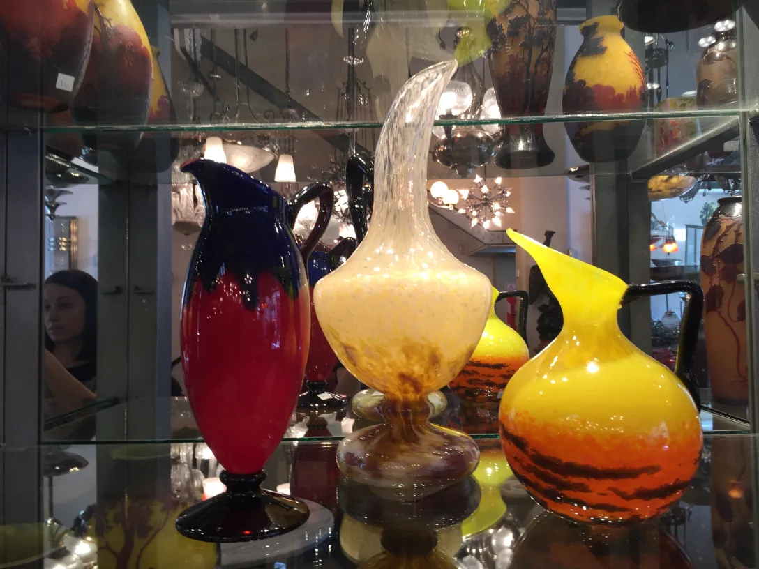 Colorful antique signed glass pitchers on display.