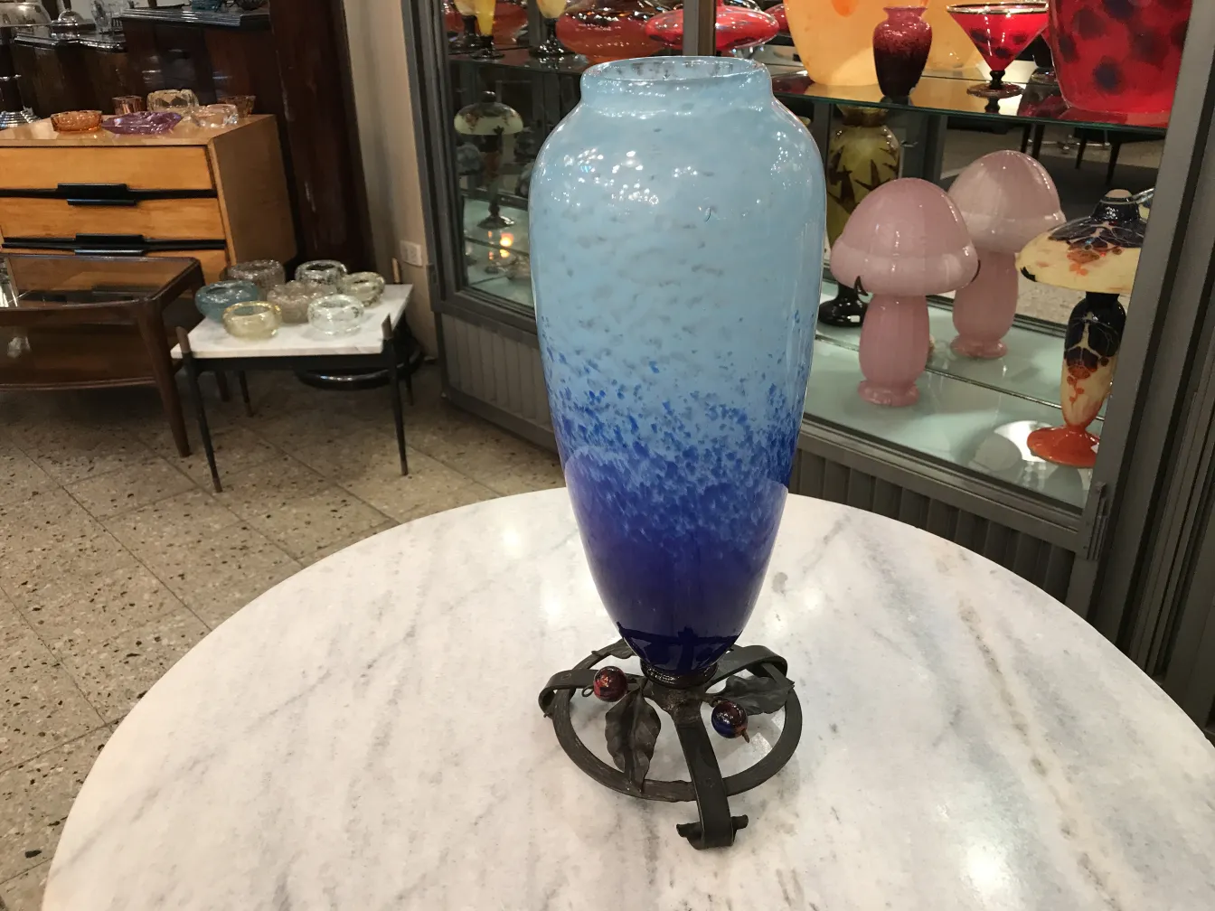blue vase with wavy design on black pedestal in antiques setting