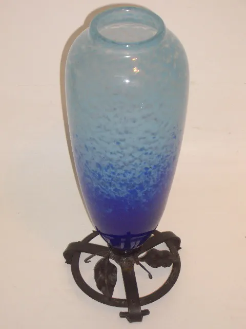 Vase ancien en verre dans des tons de bleu et clair avec support décoratif.