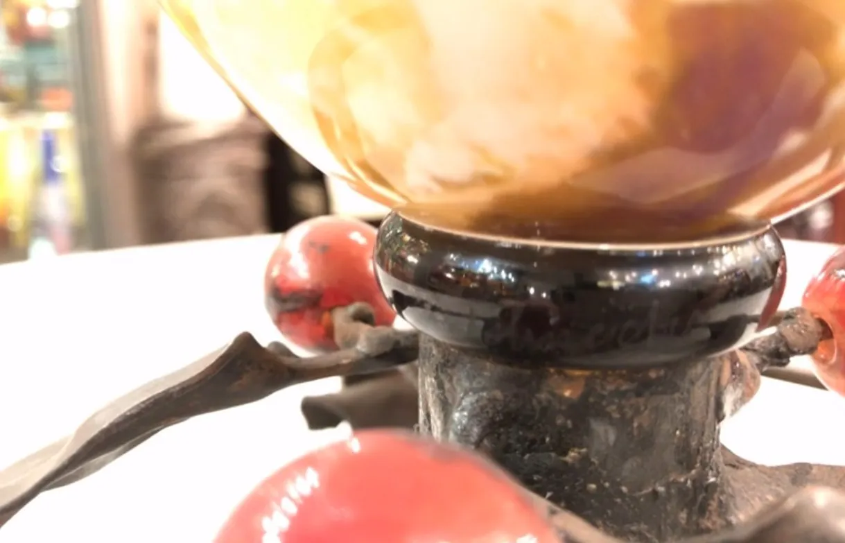 シュナイダーによるサイン入りグラス、背景に古代装飾の詳細が表示