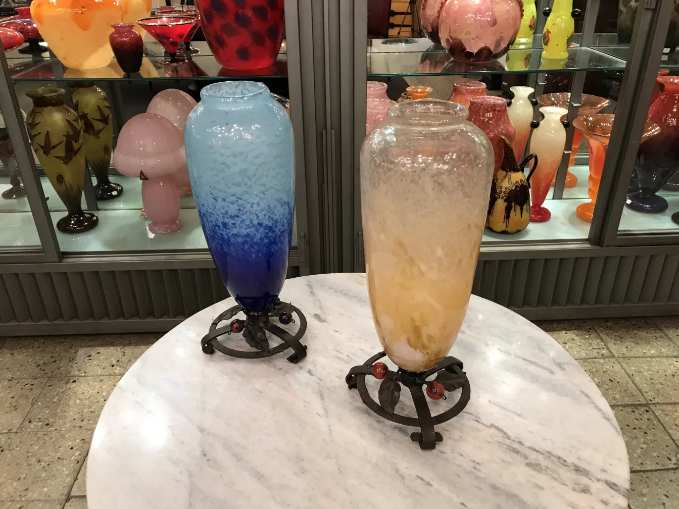 two antique signed glass vases, one blue and the other yellow, on display