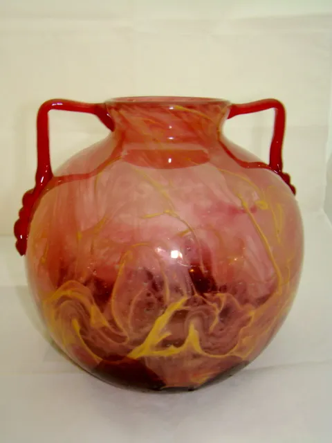 glass jug with red handles and pink-yellow swirling design