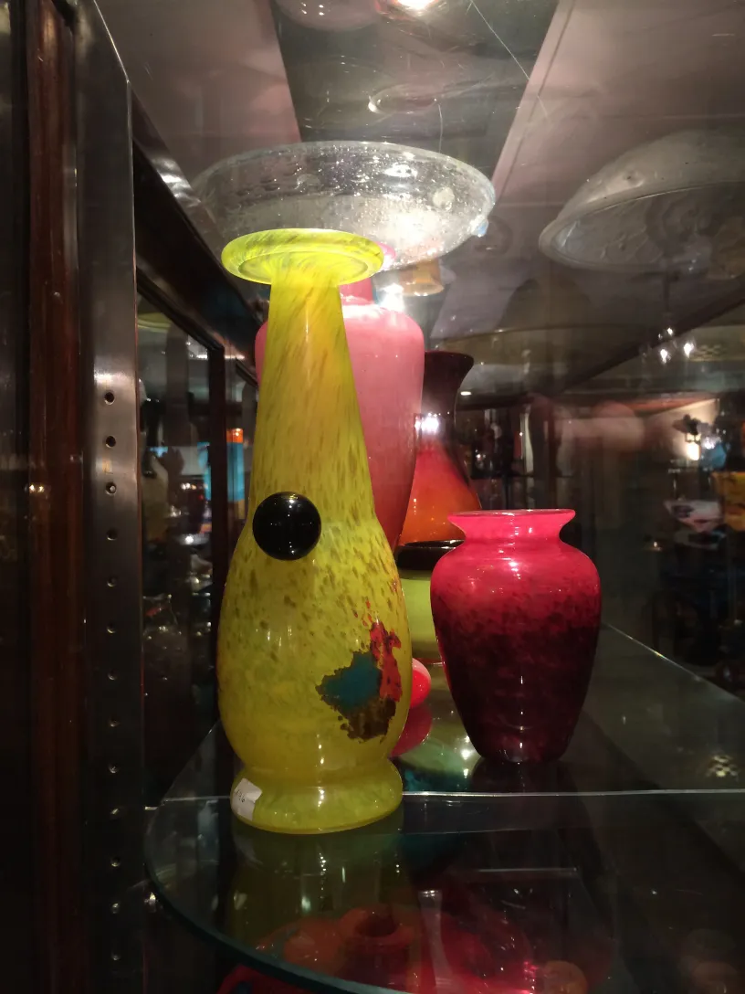 Vetro firmato d'antiquariato con design colorato e forma unica in un'esposizione accogliente.