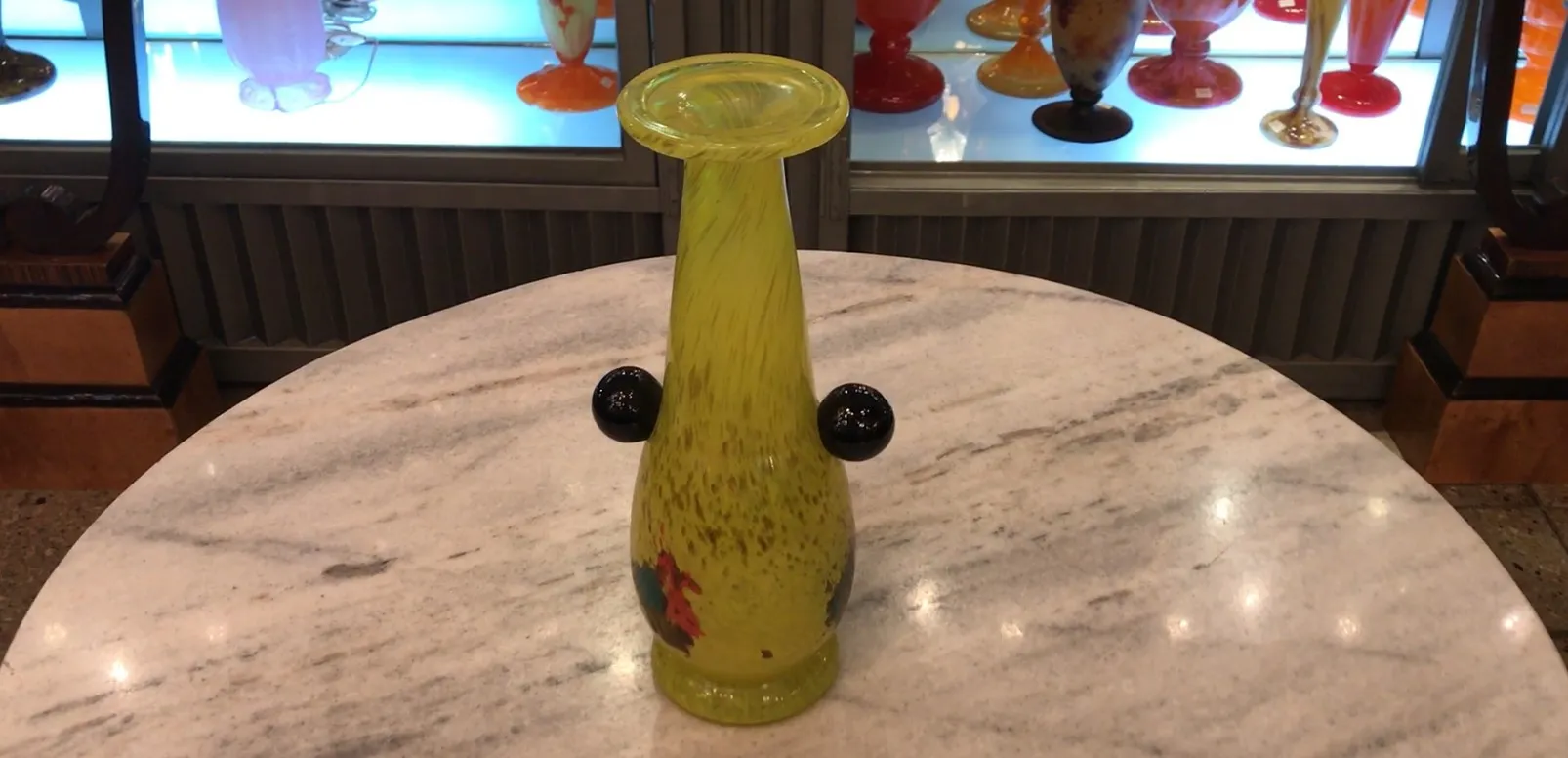 Verre signé jaune avec des détails décoratifs et une forme élégante dans un cadre d'antiquités