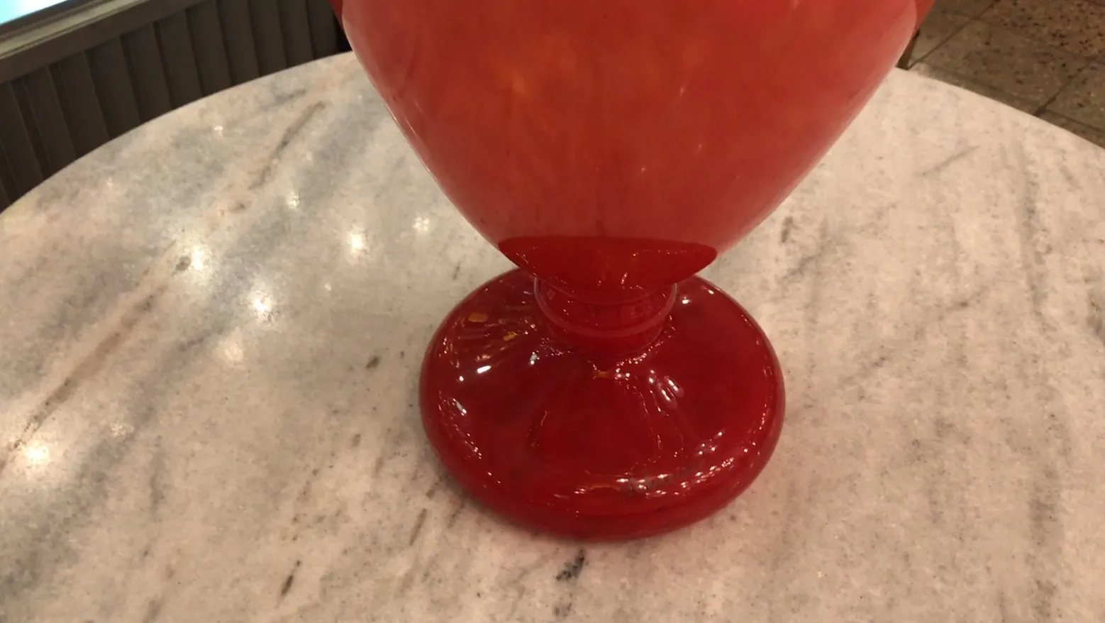 Vidrio antiguo con base roja y forma elegante firmado por Schneider, fondo neutro.