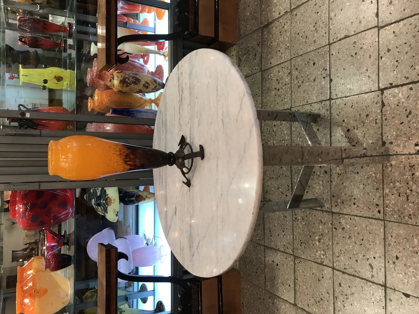 Vaso de vidrio firmado por Schneider con tonos de naranja, fondo exhibiendo otros jarrones de cristal.