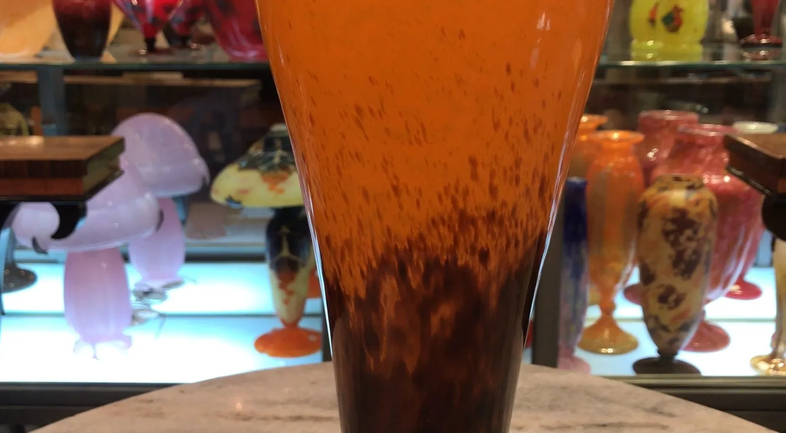 antique signed glass schneider with orange and brown hues, in a collector's environment with other pieces.