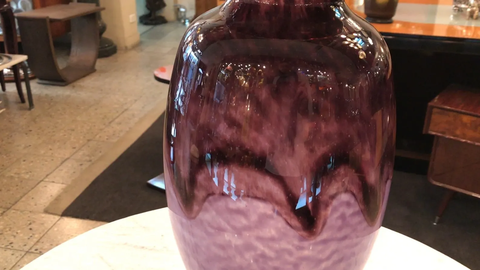 Vidrio antiguo firmado por Schneider en tonalidades moradas, en un entorno elegante.