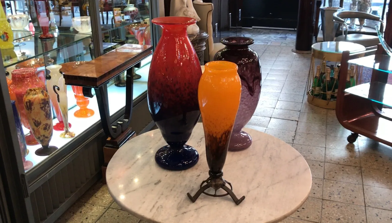Trois vases aux couleurs vives, exposés sur une table en marbre.