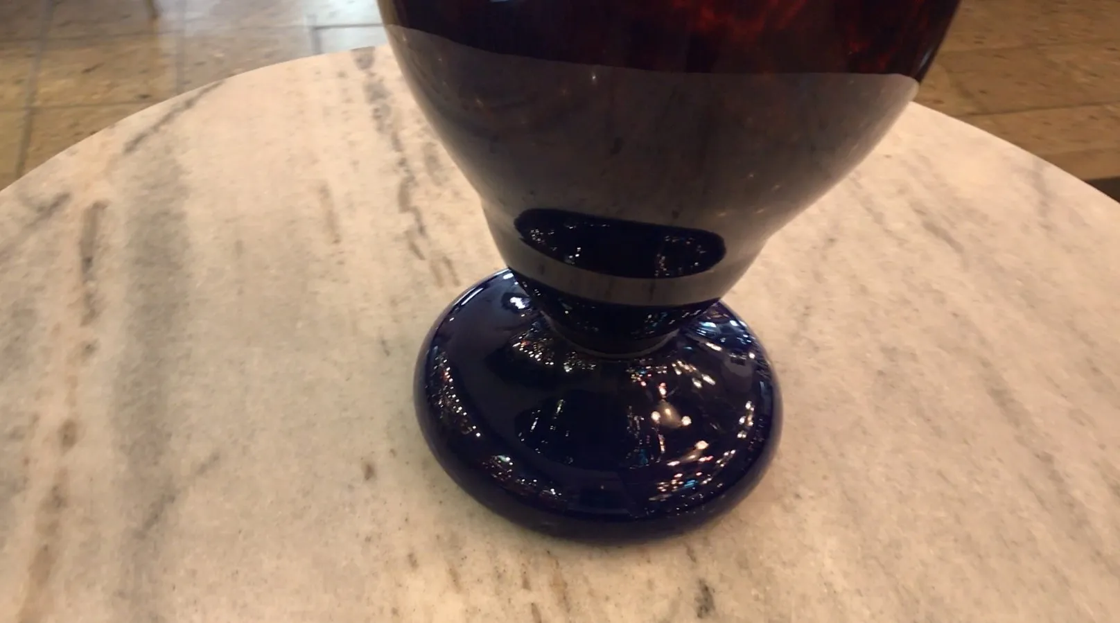 Antique signed glass Schneider on a blue pedestal with a shiny base.