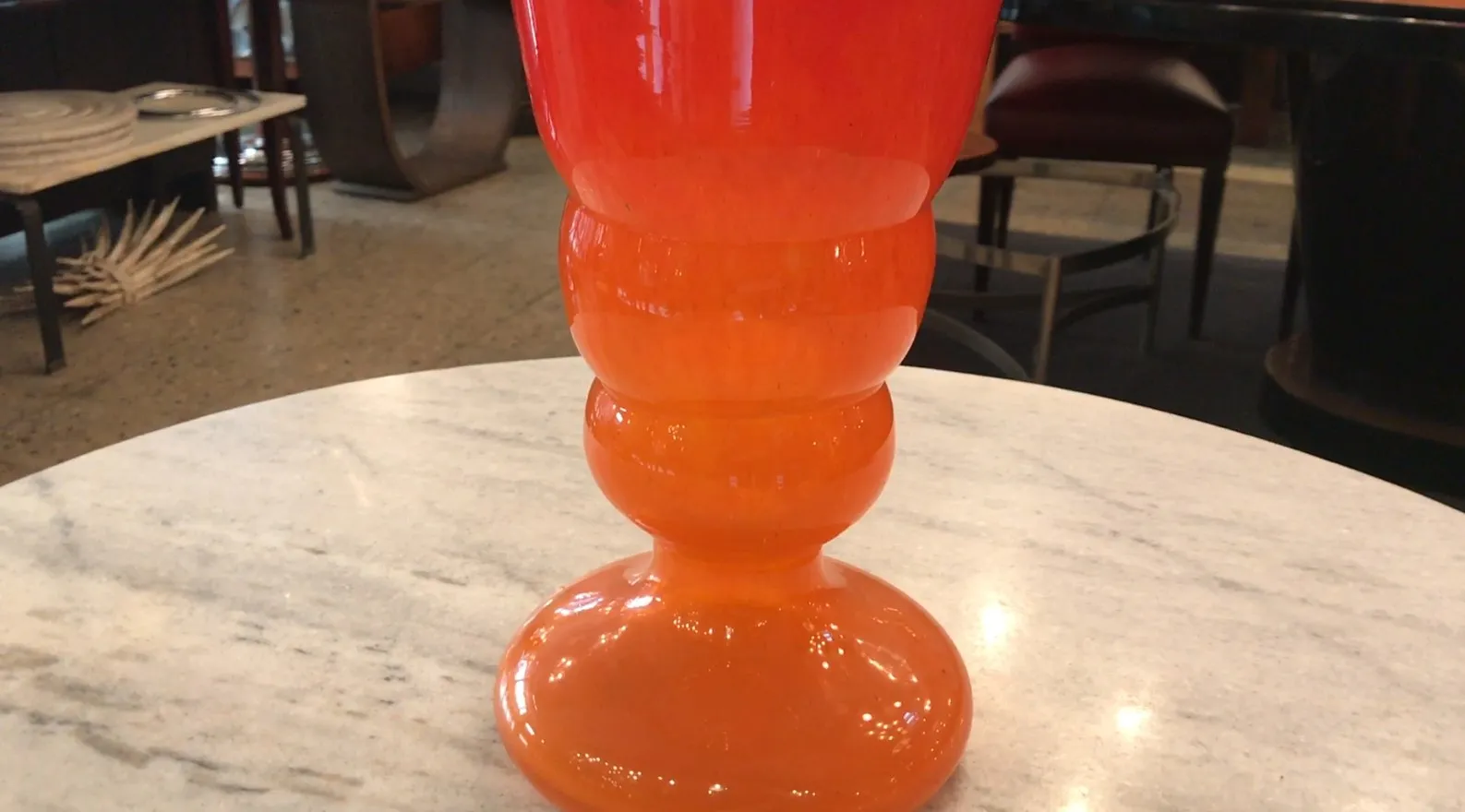 Vase ancien en tons rouges et oranges, signé par Schneider, sur une table en marbre.