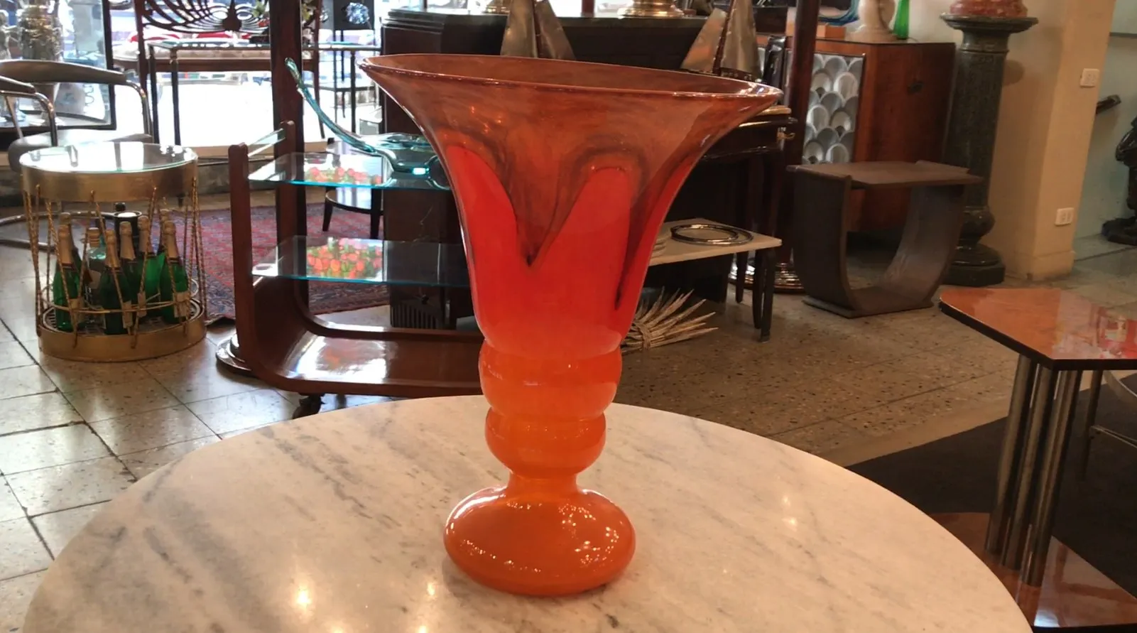Vaso antiguo de vidrio firmado por Schneider, color naranja y rojo, exhibido en un entorno decorativo.
