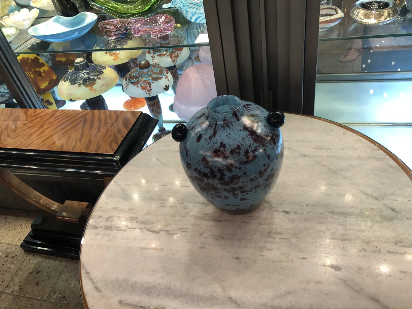 Vidro assinado com detalhes em azul e vermelho, em ambiente antigo.