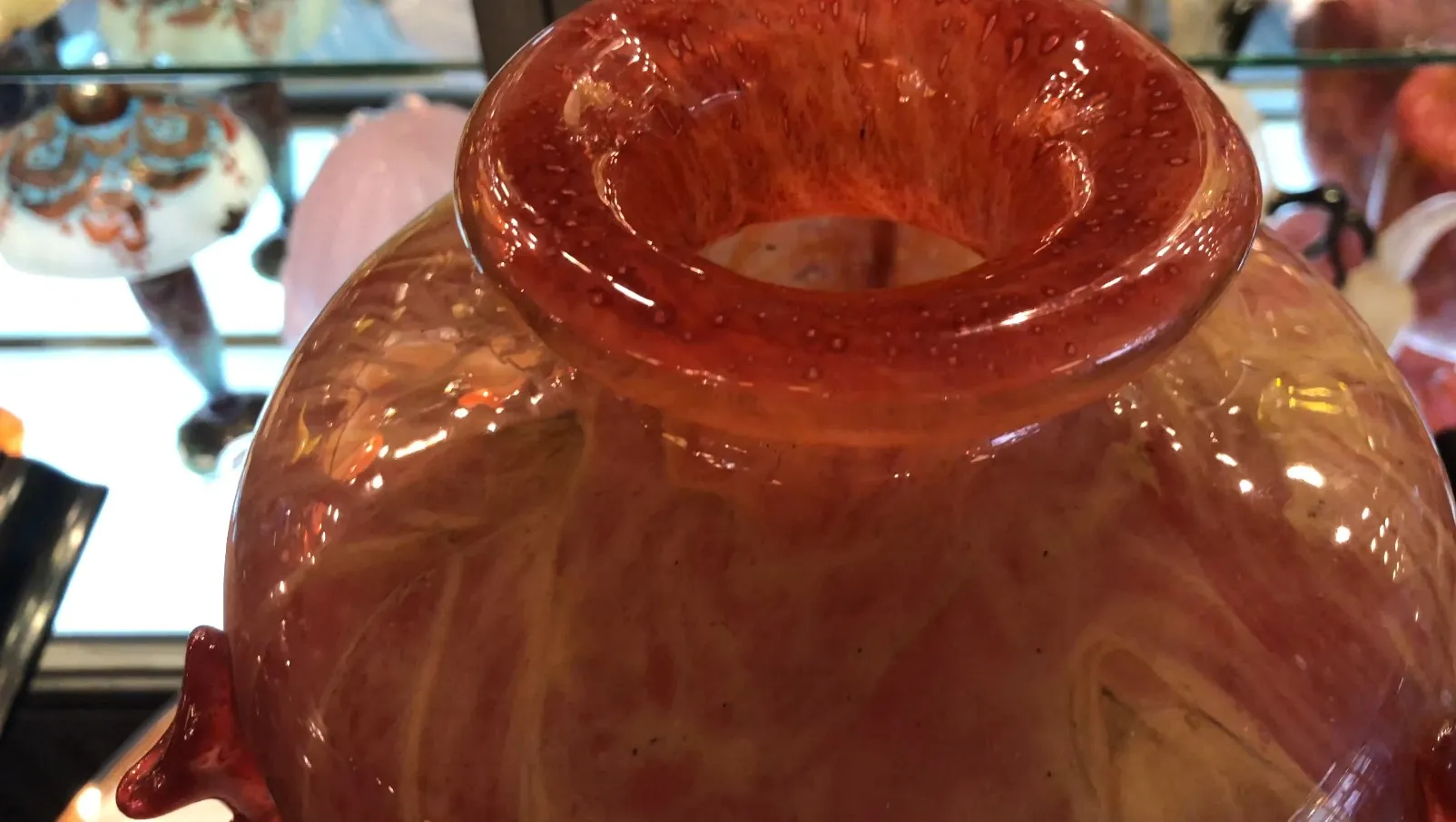 Antikes signiertes Glas von Schneider, mit orange-gelbem Design, zwischen Antiquitäten platziert.