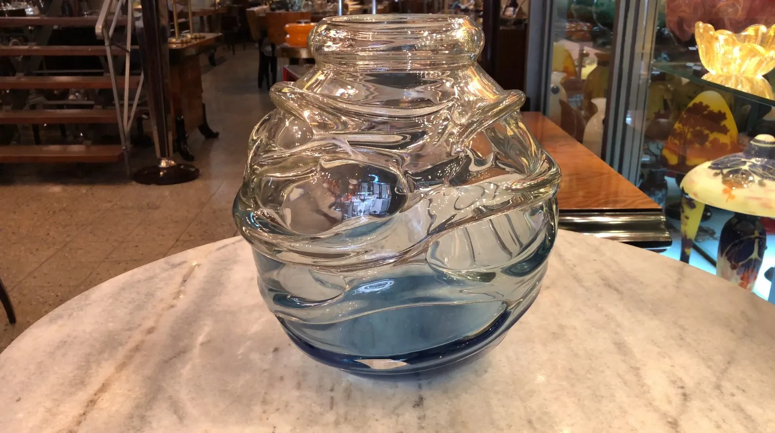 Verre signé par Schneider avec un design fluide et une couleur bleue, antiquité. Fond de galerie avec d'autres objets décoratifs.